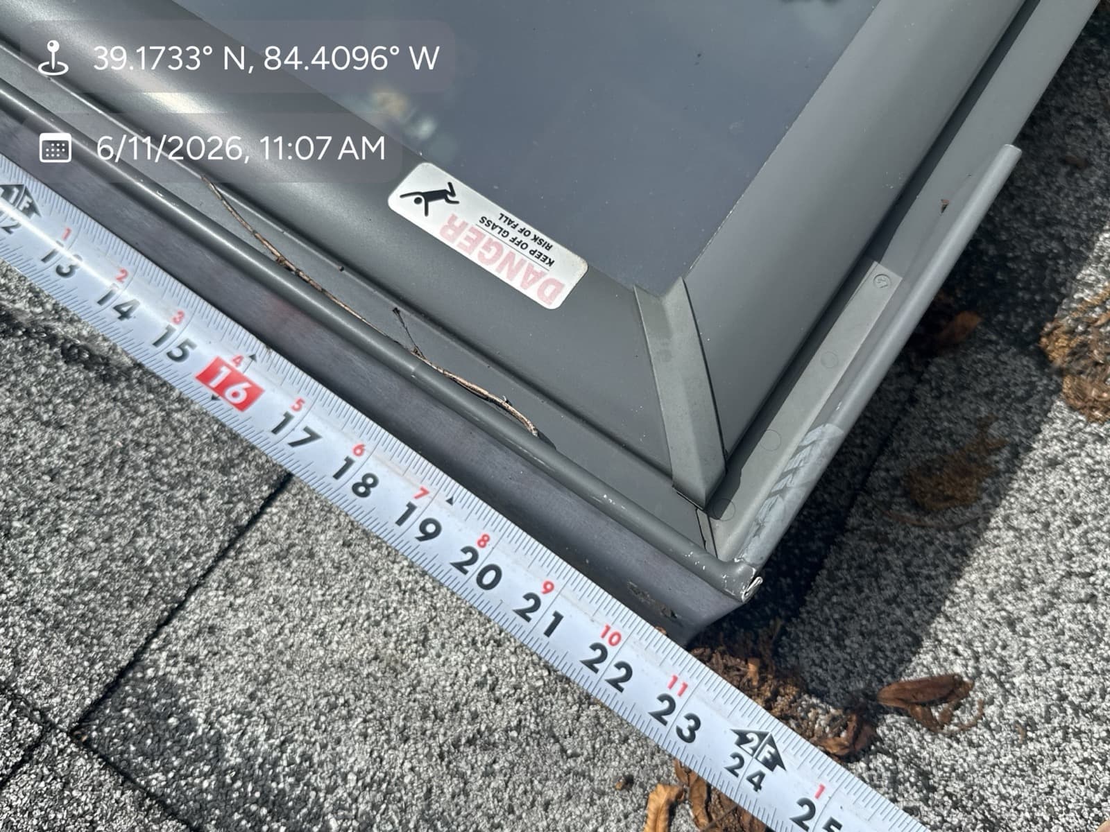 Tape measure laid across asphalt shingles documenting damage during a roof inspection